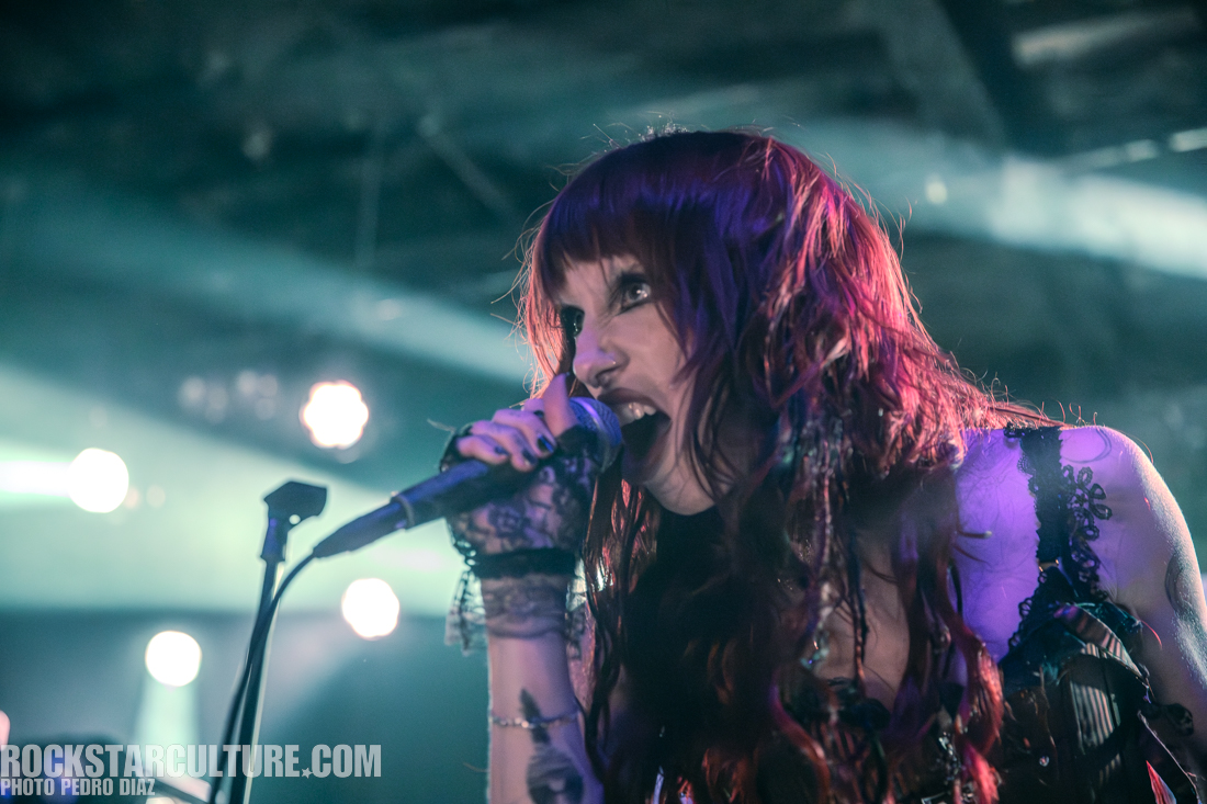 A passionate female singer performing on stage, holding a microphone and expressing intense emotions, with vibrant stage lighting in the background.
